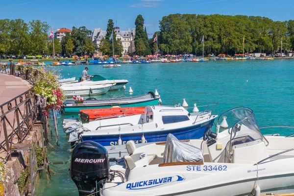 Boats moored to the flowered banks of Lake Annecy in the French Alps in France