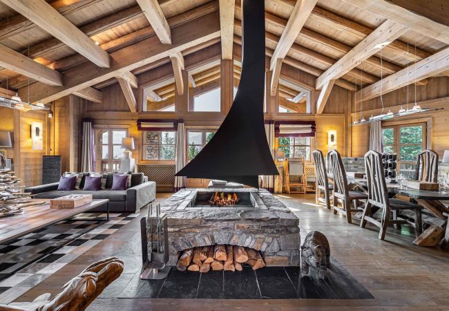 Open-plan living space with contemporary central fireplace and bay windows offering sunny views over Courchevel.