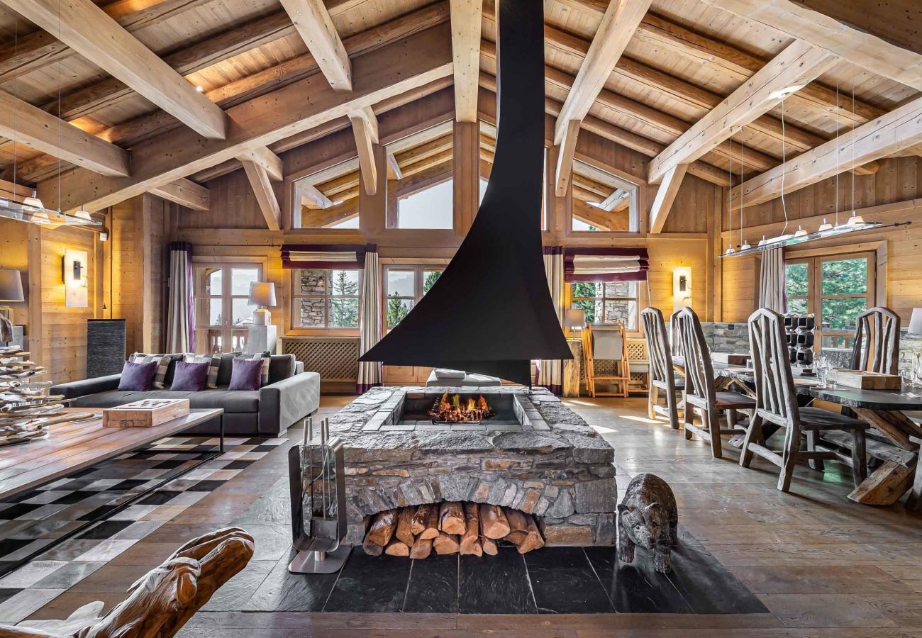 Open-plan living space with contemporary central fireplace and bay windows offering sunny views over Courchevel.
