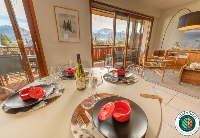Salle à manger lumineuse avec accès au balcon offrant une vue imprenable sur les montagnes d'Annecy 