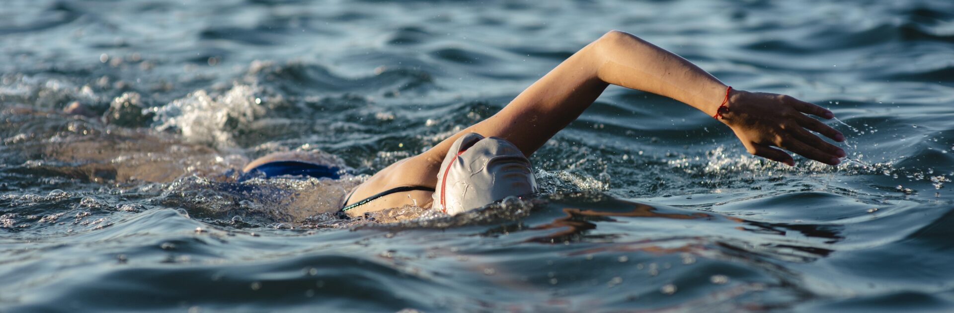 Femme portant un bonnet de bain, nageant au milieu d’un lac.