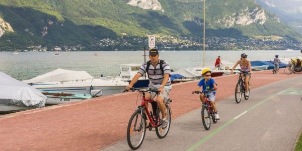 Annecy, France - August 26, 2013: Tourists on the bike path around the lake. The bike path is separated from the roadway, and runs along the lakeside for 36 kilometers (22 miles). Along the bike path, customers can rent bikes and take advantage of a repair service.
