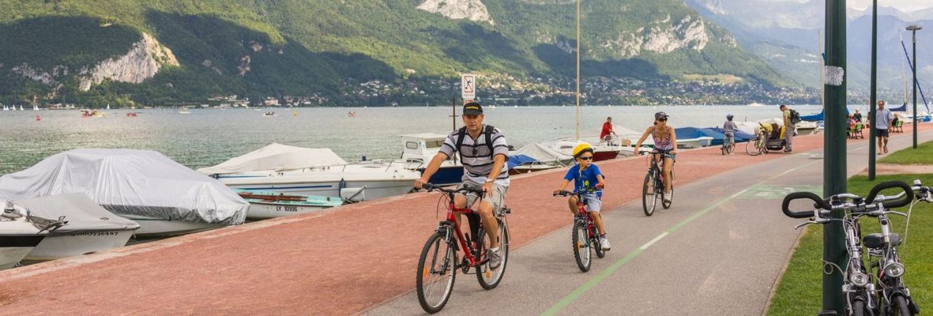 Annecy, France - August 26, 2013: Tourists on the bike path around the lake. The bike path is separated from the roadway, and runs along the lakeside for 36 kilometers (22 miles). Along the bike path, customers can rent bikes and take advantage of a repair service.